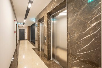 Interior of a marble corridor with stainless steel elevator doors