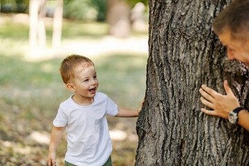 A son playing seek and hide with his father in woods.