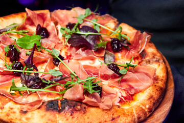 Pizza with ham and dried cherries. Close-up, selective focus