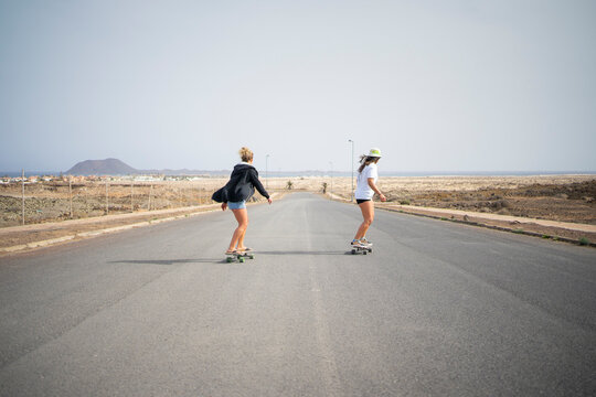Friends skateboarding together on sunny day