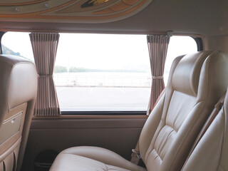 Empty brown leather seats in van with outdoor view. - 495373641