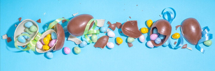 Happy Easter colorful flatlay. Bright high-colored and chocolate Easter eggs with festive holiday ribbon on blue background. Promotion and shopping template for Easter