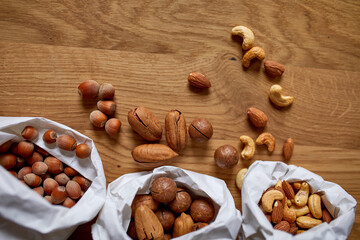 Top view Various sort of nuts on the table in a paper bag on wooden background, shopping grocery concept,  nuts delivary,  Zero Waste Food Shopping. Copy space..