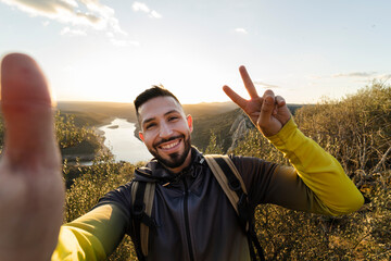 Male hiker making peace gesture while taking selfie in Monfrague National Park