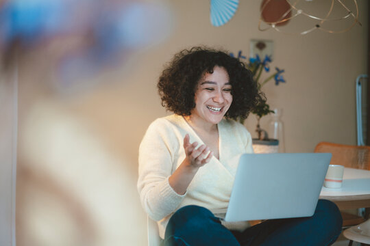 Happy woman video calling on laptop at home