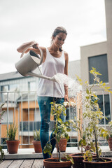 Smiling woman watering plants at balcony