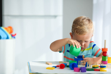A little boy plays with wooden toys and builds a tower. Educational logic toys for children. Montessori games for child development. Children's wooden toy.