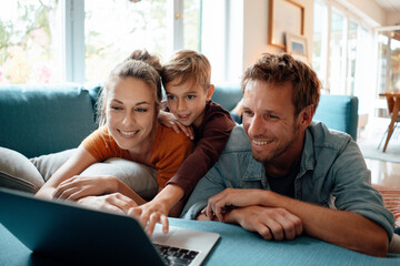 Happy mother and father with son watching video on laptop at home