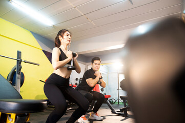 Image of an attractive woman working out with a personal trainer at a gym in Asia.