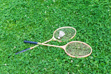 Badminton rackets with a shuttlecock on the lawn.