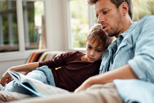 Man reading book to son at home