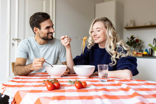 Couple eating food together on dining table at home - Powered by Adobe
