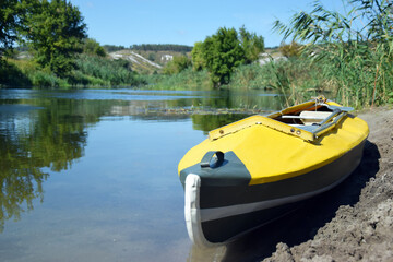 Yellow bright kayak lies on the bank of the Oskol river.