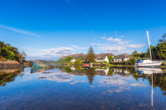 Picturesque Plockton village and boat reflecting on lake, Scotland