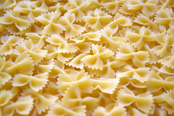 A lot of pasta in the shape of a butterfly on the table as a background.