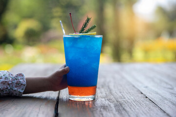 women Handle holding Ice water italian soda purple in glass with citrus and rosemary  , Ice butterfly pea beverage healthy.