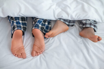 Gay couple with bare feet resting in their bedroom