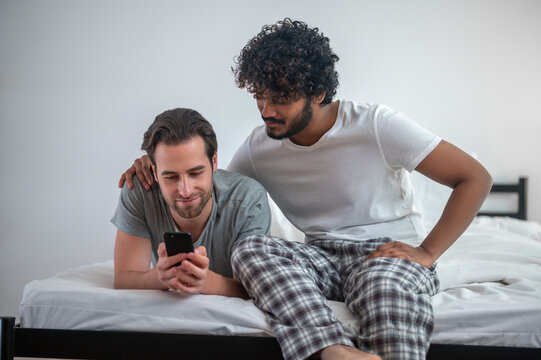 Concentrated gay couple viewing selfies on the cellphone