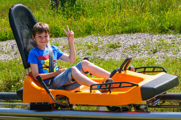 Gutgelaunter Jugendlicher freut sich auf die rasante Fahrt auf der Sommerrodelbahn im Coaster