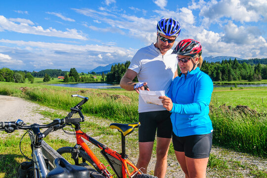 Gutgelauntes Paar orientiert sich auf einer Landkarte bei einer Radtour im Ostallg&auml;u