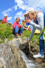 Trinkpause beim Wandern an einem frischen Gebirgsbach