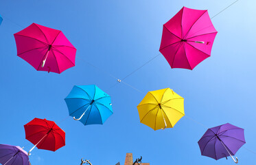 Colorful umbrellas hanging from cables in mid air