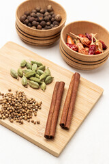 Cinnamon sticks, coriander seeds and cardamom on wooden board.