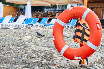 Lifebuoy on a pebble beach against the background of sun loungers