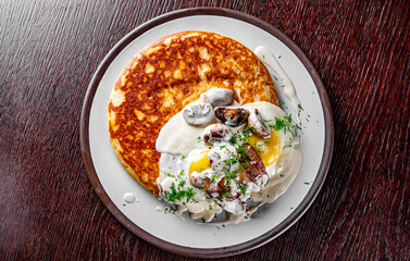 pancake with mushroom sauce, bacon and egg on plate
