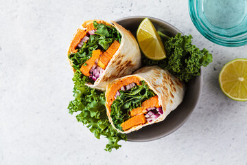 Vegan burrito wrap with sweet potato, kale and onion. Vegetarian food concept. - obrazy, fototapety, plakaty