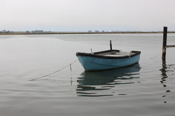 Old small blue fishing boat on water