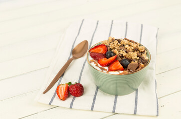 strawberry blueberry granola bowl on wooden white background