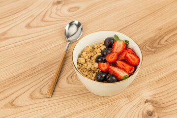 strawberry blueberry granola bowl on wooden floor