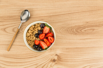 strawberry blueberry granola bowl on wooden floor