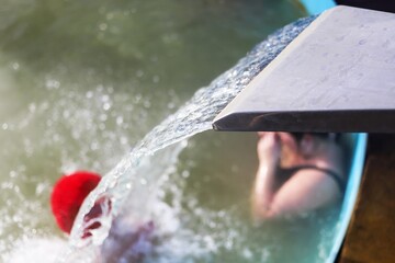 a jet of water at a spa resort pours from above the heads of vacationers in winter it is not cold