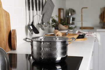 Metal pot on cooktop in kitchen. Cooking utensils