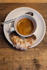 cup of coffee with a nut coated cookie 