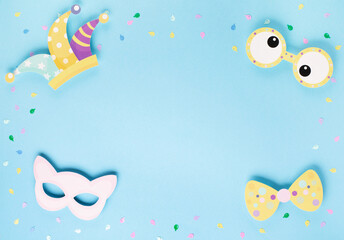 April Fool's Day holiday card with Jester hat, confetti and funny glasses on blue background, top view.