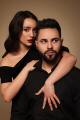 Handsome bearded man with sexy lady on light brown background
