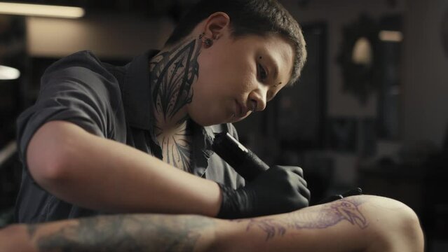 Focus caucasian woman tattooing arms of her customer. Shot with RED helium camera in 8K.  