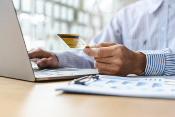 Close up businessman using credit card for paying bills online.