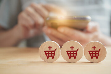 shopping cart icon with plus on circle wood with blur senior woman holding smart phone for customer target, e commerce, social media promotion concept