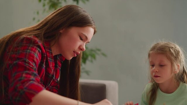 Concentrated girl looks at long haired sister mixing colors
