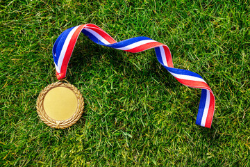 Gold medal on grass of track and field with blank face for text, concept for winning or success