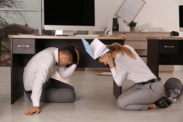Scared employees on floor in office during earthquake