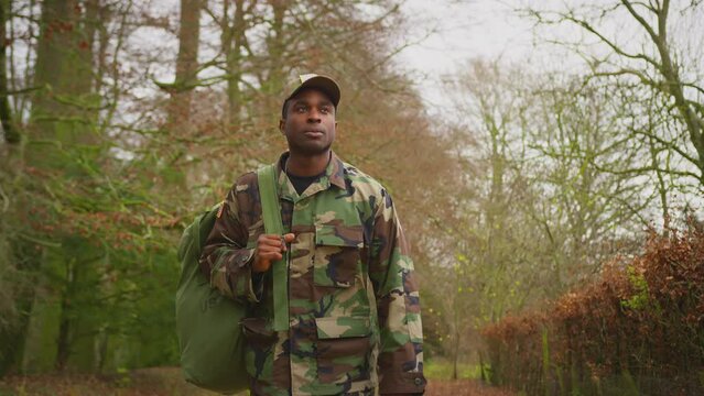 Front view of soldier in camouflage uniform carrying kit bag walking home to see family on leave - shot in slow motion