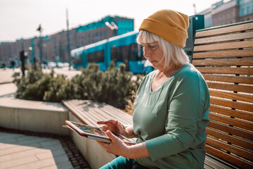 Mature woman in city walking using tablet computer
