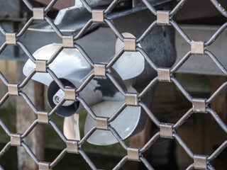 Propeller of the boat in the boathouse as seeing through the fence but with focus on the fence
