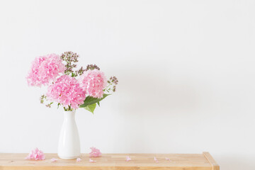 pink   hydrangea in white vase on wooden shelf  on background white wall