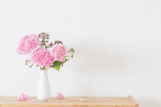 pink   hydrangea in white vase on wooden shelf  on background white wall